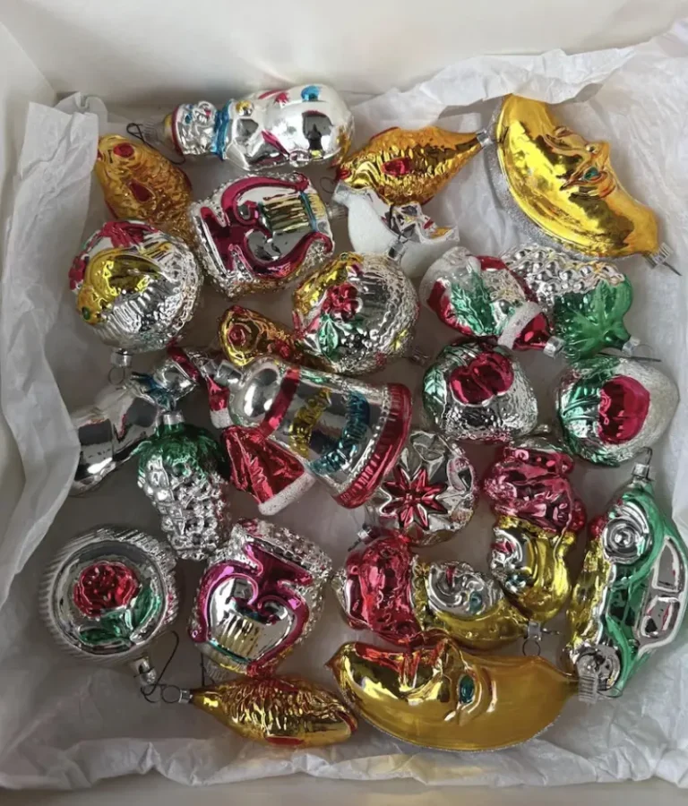 An assortment of shiny and bright German nostalgie ornaments, including roses, a moon, car, snowman, and fruit shapes.