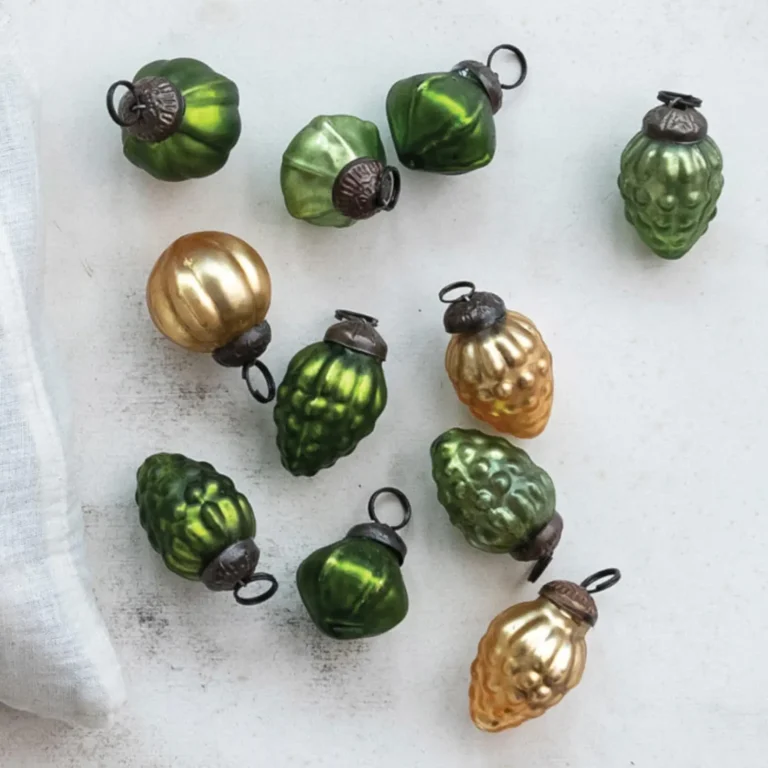 Small gold-tone and olive green vintage Christmas tree ornaments spread out on a white surface.