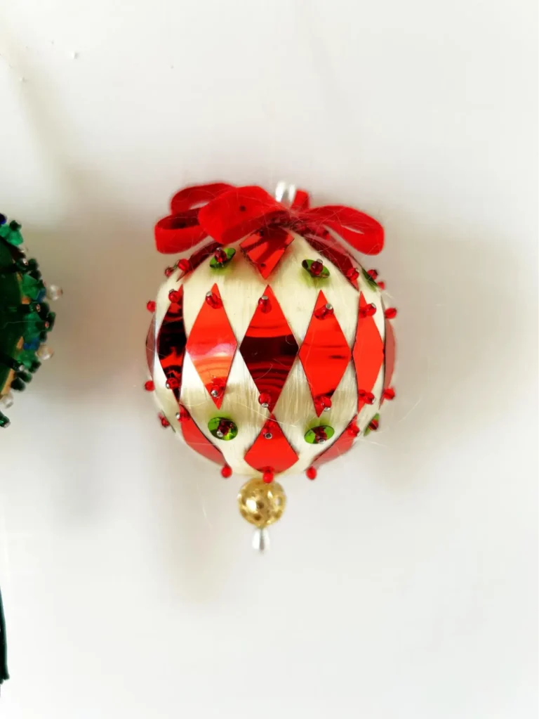A vintage round push-pin ball Christmas tree ornament featuring red diamond-shaped sequins, beads, and faux pearls.