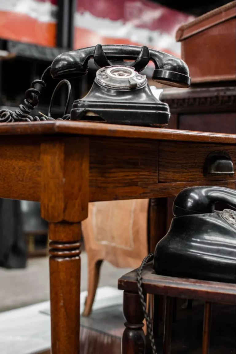 A black rotary phone sitting on a wooden desk as part of vintage office decor.