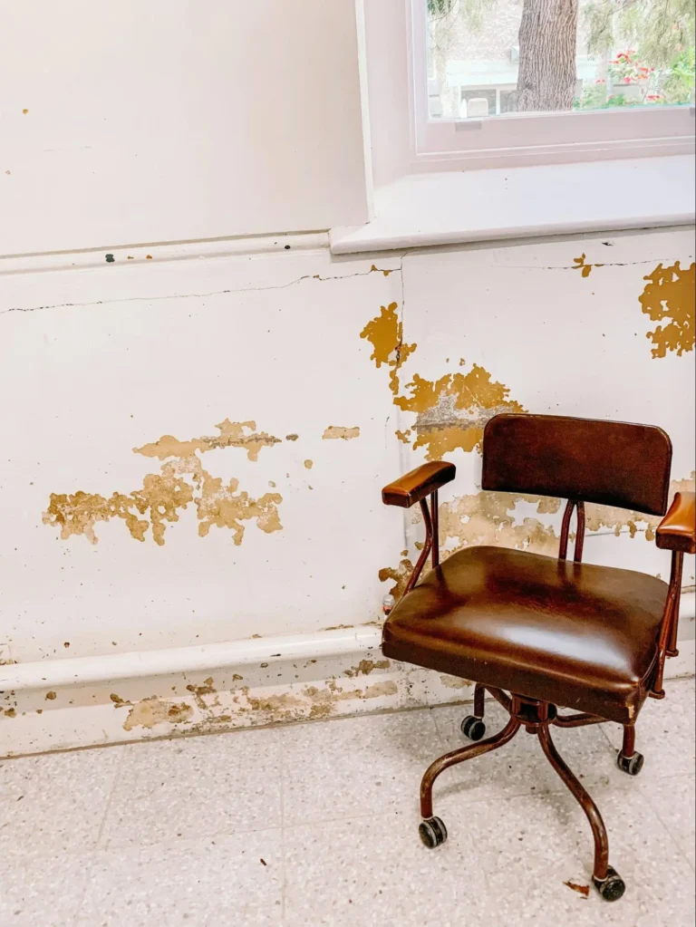 A vintage leather swivel chair set against a worn-out, scratched wall.