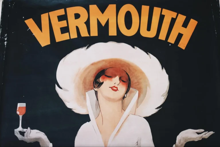 Top half of a vintage vermouth poster depicting a lady in a white hat and white apparel, holding a glass of vermouth.