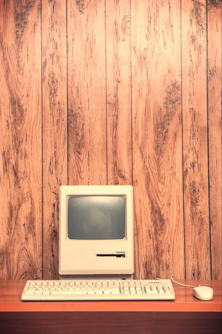 An old school desktop computer with vintage wooden wall panels in the background.