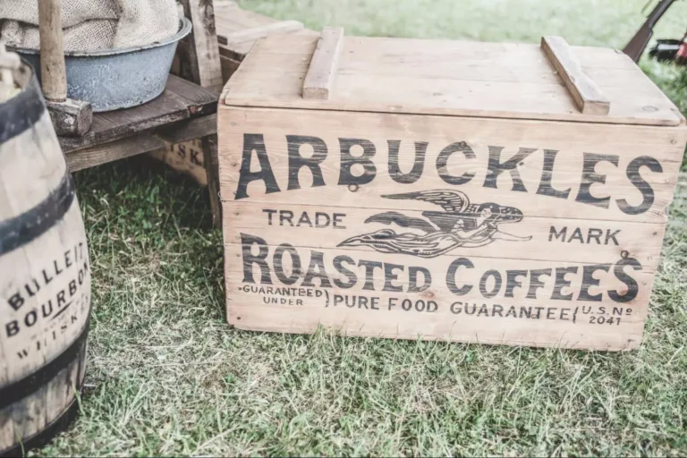 A vintage wooden farmhouse crate with a logo imprinted on it, lying on grass.