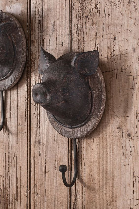 A cast-iron wall hanger in the shape of a pig’s head, hanging on a wooden vintage wall.