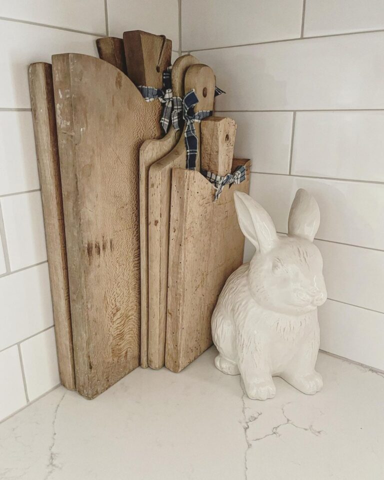 Rustic cutting boards and a porcelain figure of a bunny on a marble kitchen countertop.