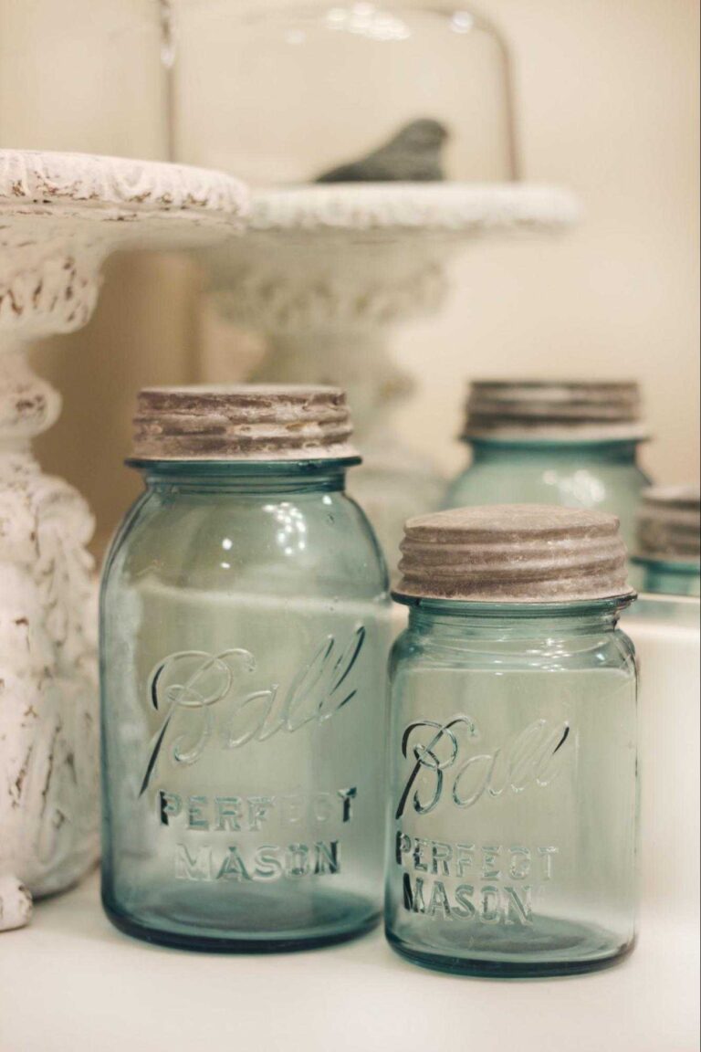 Blue vintage Mason jars are displayed on a bathroom countertop as part of vintage farmhouse-style decor.