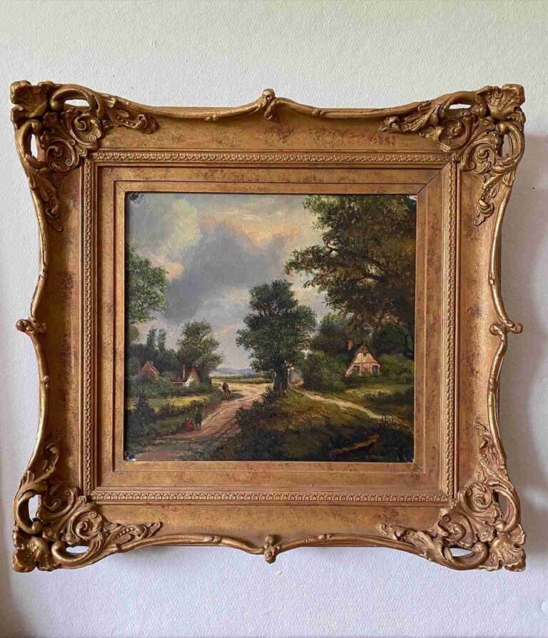 An old square-shaped painting of a pastoral scene featuring trees, a village road, a couple of cottage homes, and three distant figures, encased in an ornate gilded frame.