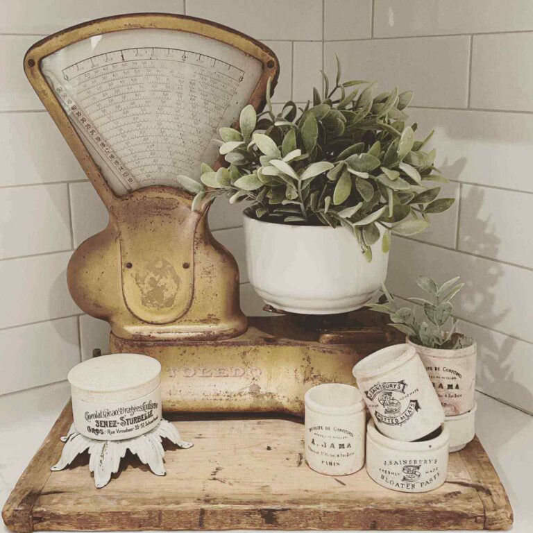 An old kitchen scale decorated with vintage French kitchen ceramics and a potted plant.