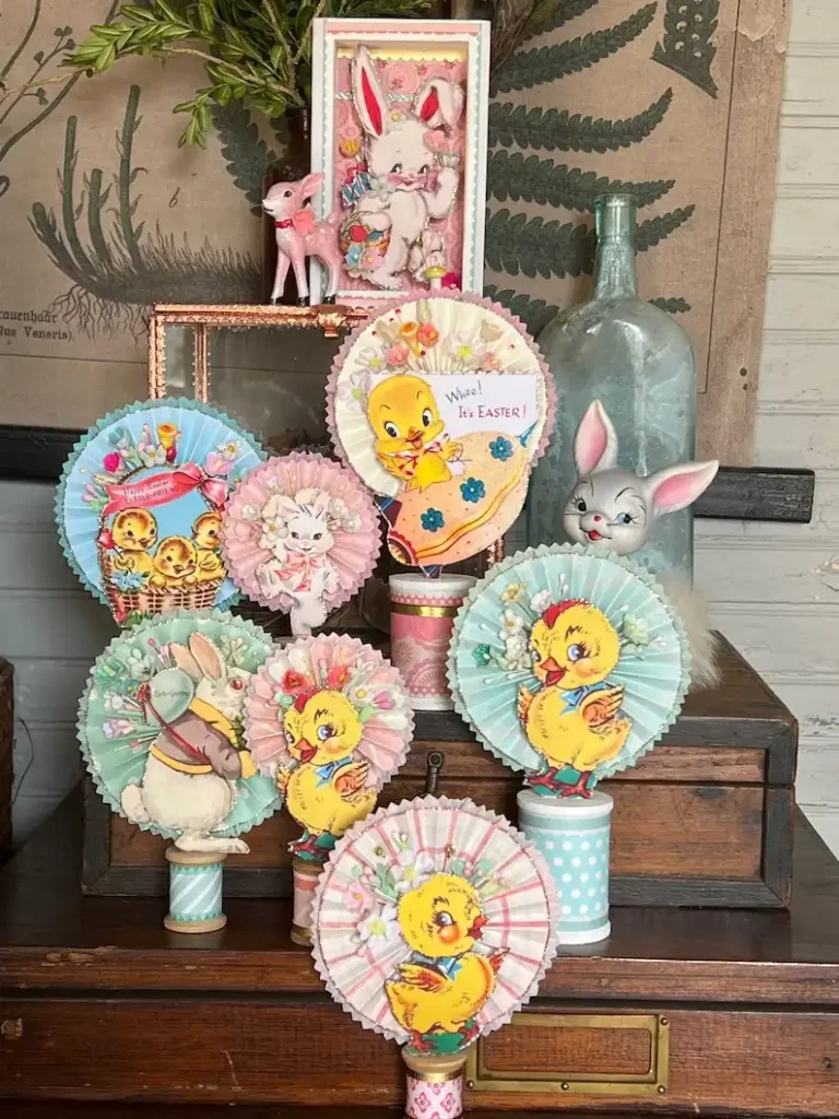 Eight vintage kitsch Easter paper decorations featuring chicks and bunnies displayed on wooden furniture.