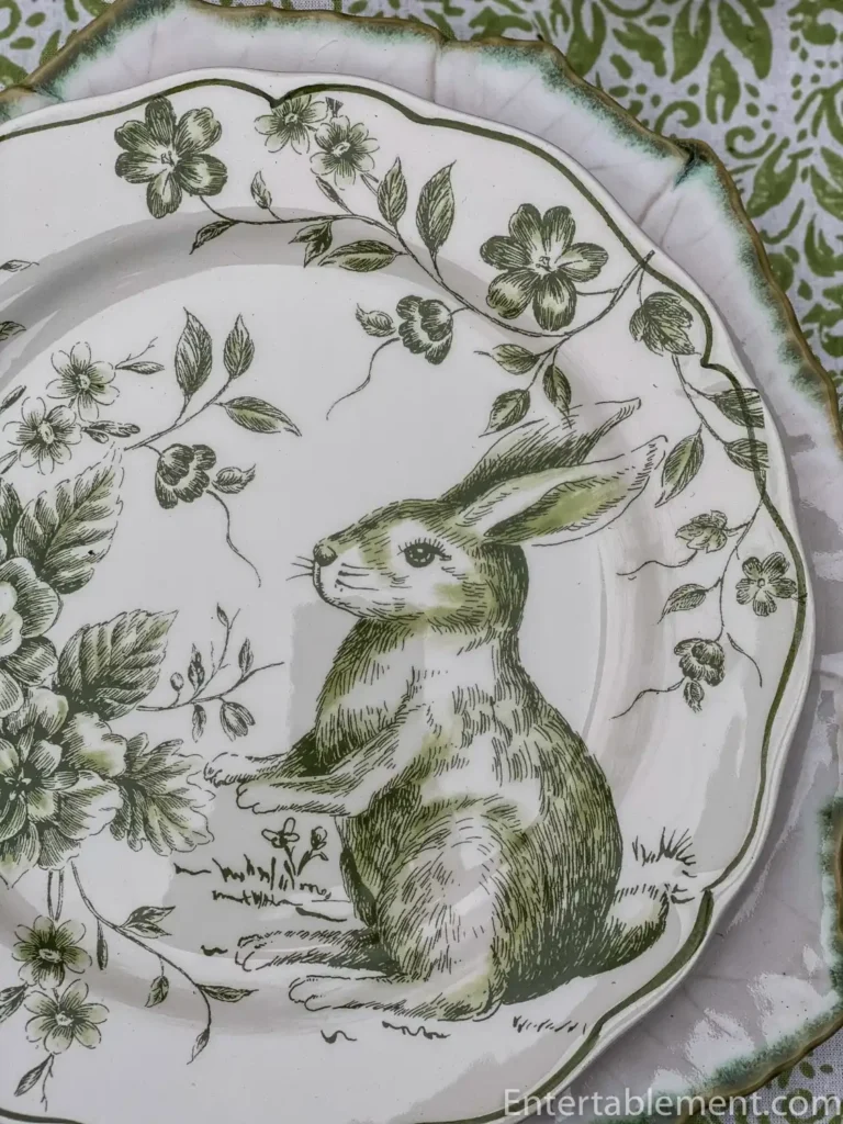 A green and white vintage English transferware plate featuring a vintage illustration of a rabbit and floral motifs.