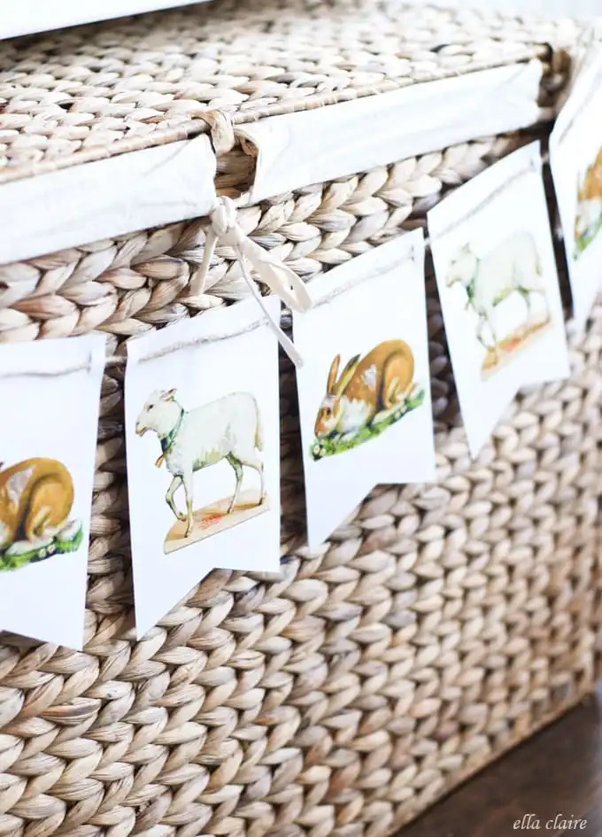 An Easter bunting made out of vintage Easter illustrations printed on white fabric, hanging on a water hyacinth basket.