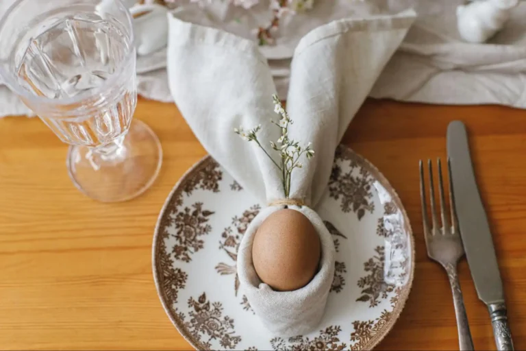 Easter egg in a bunny-shaped linen napkin on a vintage plate with silverware.