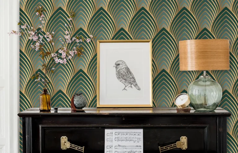 A vintage black piano decorated with a print of a bird drawing in a gold frame, a vintage lamp, cherry blossoms in a dark brown glass bottle, and a gold table clock. A green and gold Great Gatsby-inspired wallpaper is seen in the background.