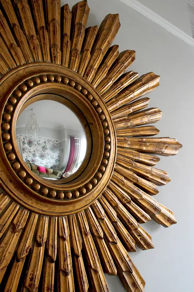 A partial view of a gilded brass sunburst mirror – an element of old Hollywood glamour decor.