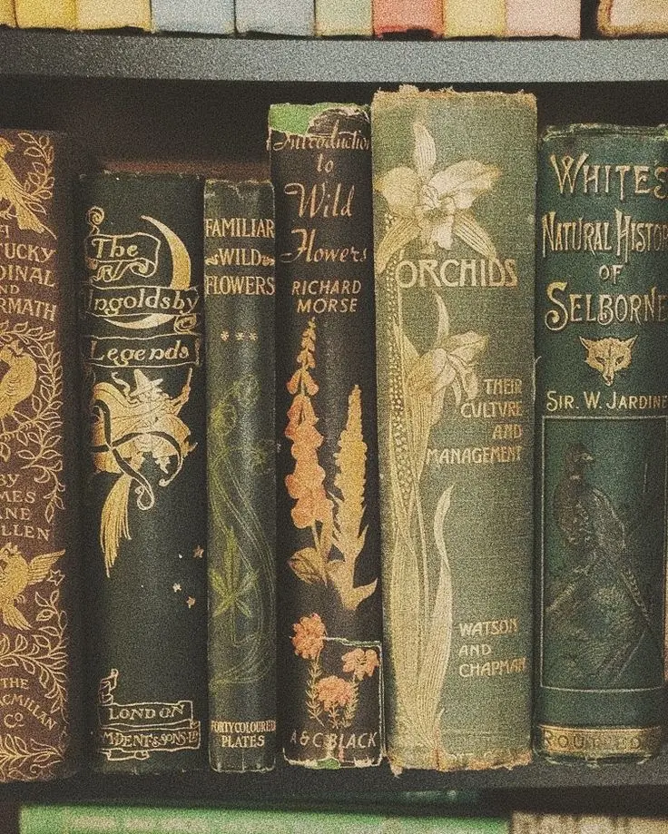 Six ornately decorated antique books of various green shades about the topic of flowers, gardening, and horticulture lined up next to one another.