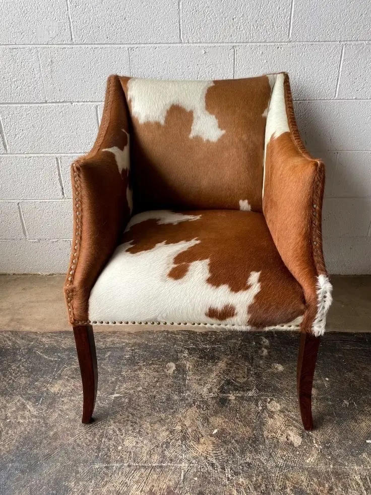 The frontal view of a vintage armchair upholstered in brown and white cowhide.