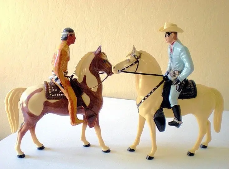 Two vintage figurines: one of a Native American man on a white and brown horse and the other of a white cowboy on a white horse.