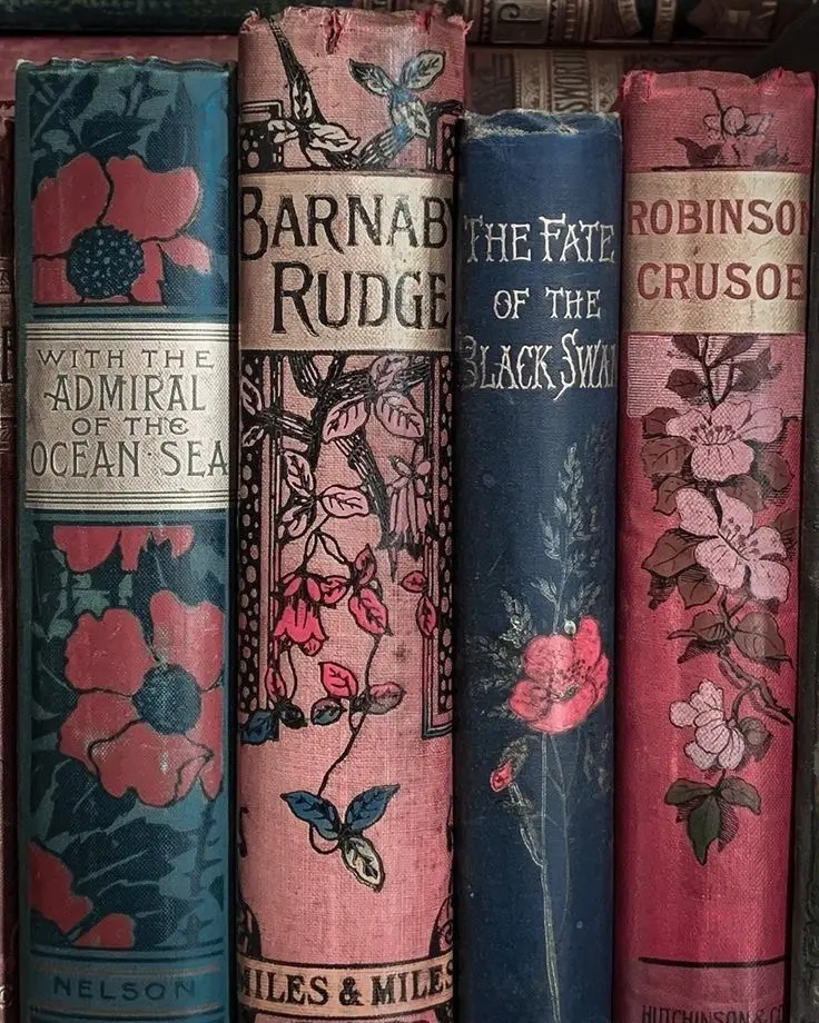 Four blue and rose pink books featuring floral designs and vintage fonts lined up next to each other.