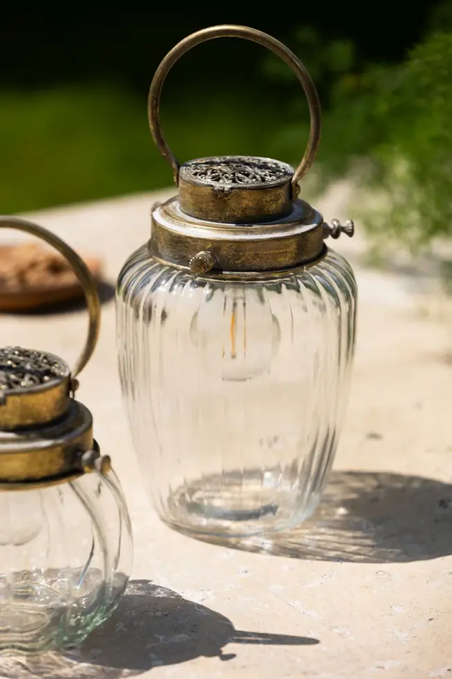 A vintage-style glass lantern with a brass handle.