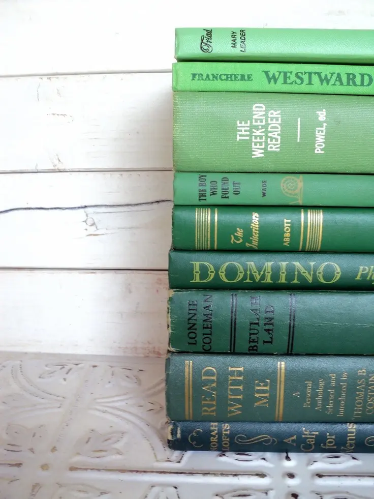 A stack of vintage books arranged to form a color transition from dark blue to lime green.