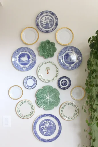 A vertical gallery wall made up of blue and white blue willow plates, cabbage-shaped plates, and other vintage china.