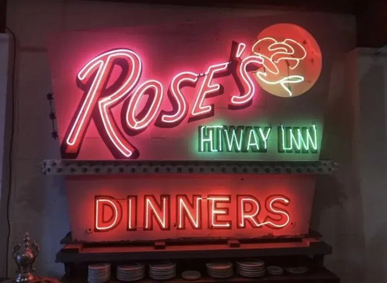 A pink, green, and red neon that says “Rose’s Hiway Inn Dinners” with a neon rose.