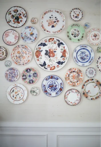 A gallery wall made up of small, medium, and large round plates featuring floral and botanical designs in various colors.