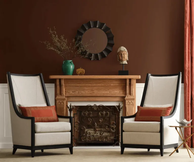 A vintage-style interior with an antique-style mantelpiece and two high barrel chairs in cream and black, with the wall painted French Roast and Oyster White by Sherwin-Williams.