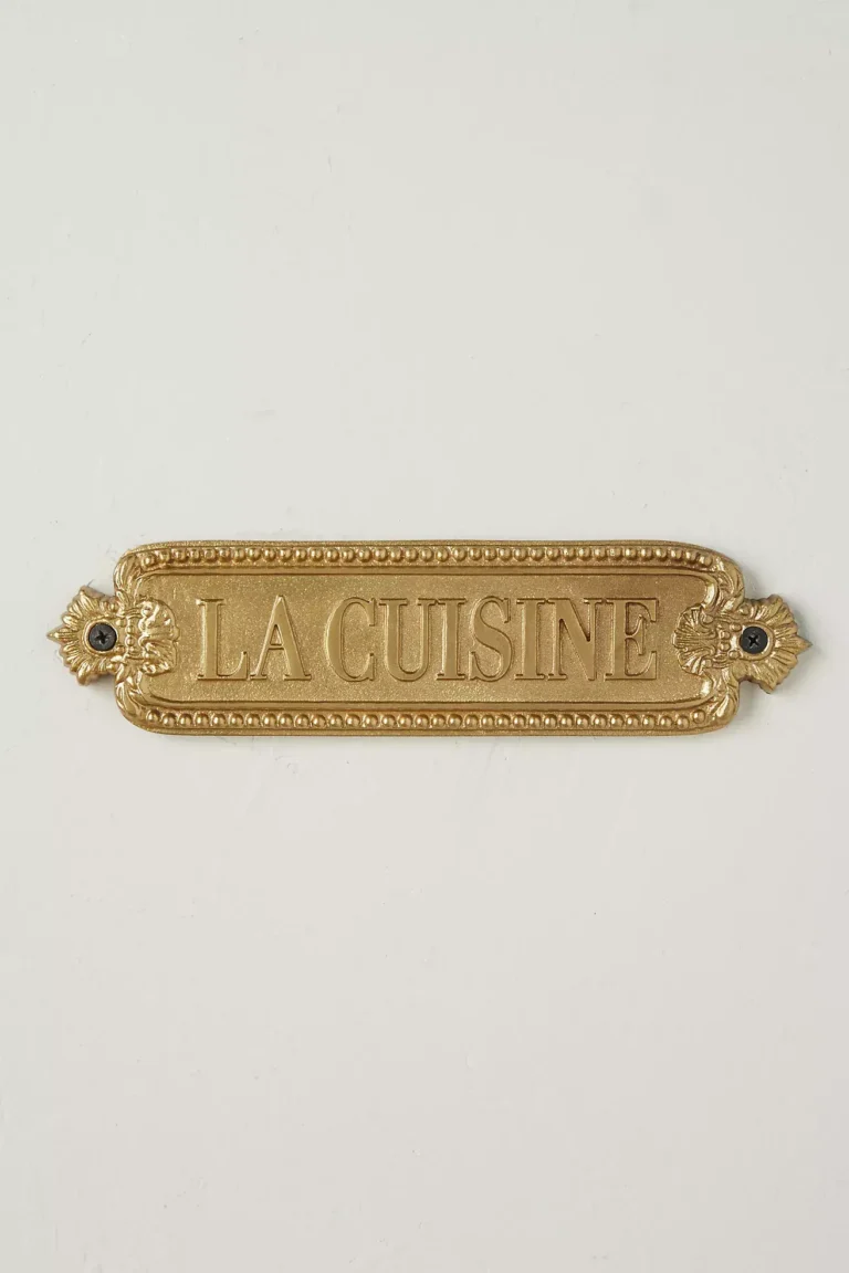 An antique-style rectangular brass sign reading la cuisine.