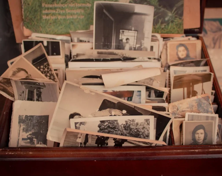 A collection of old black and white photos in an open old wooden drawer.