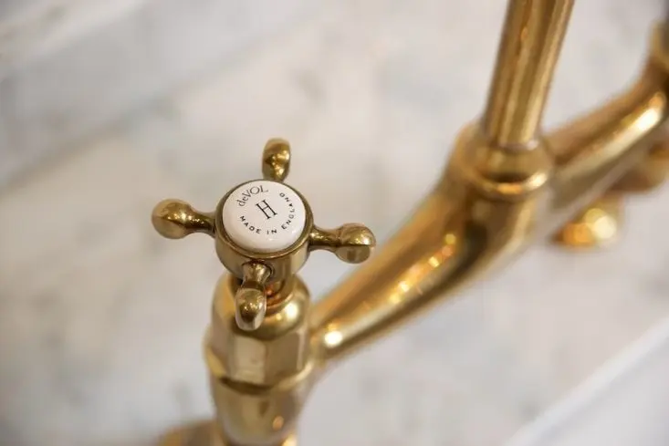 A closeup view of a vintage-style brass faucet and faucet handle.