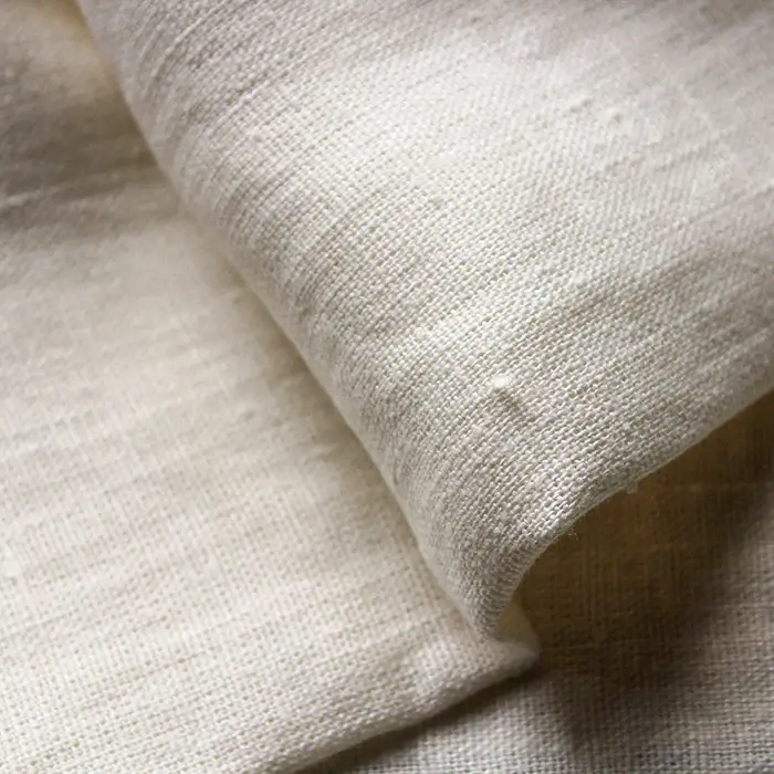 A closeup view of a textured, cream-colored French linen fabric.