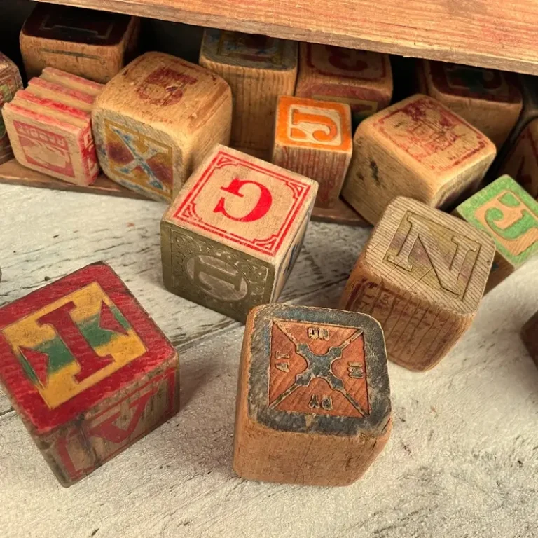 Large vintage wooden playing blocks with letters scattered on a wooden surface.