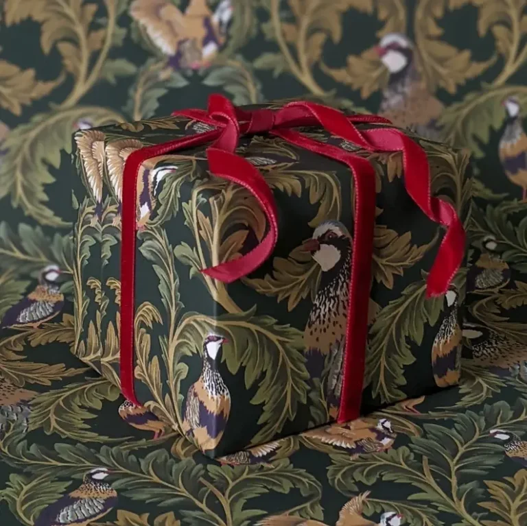 A gift wrapped in antique-style Christmas gift-wrapping paper featuring a bird and acanthus leaf illustration by William Morris.