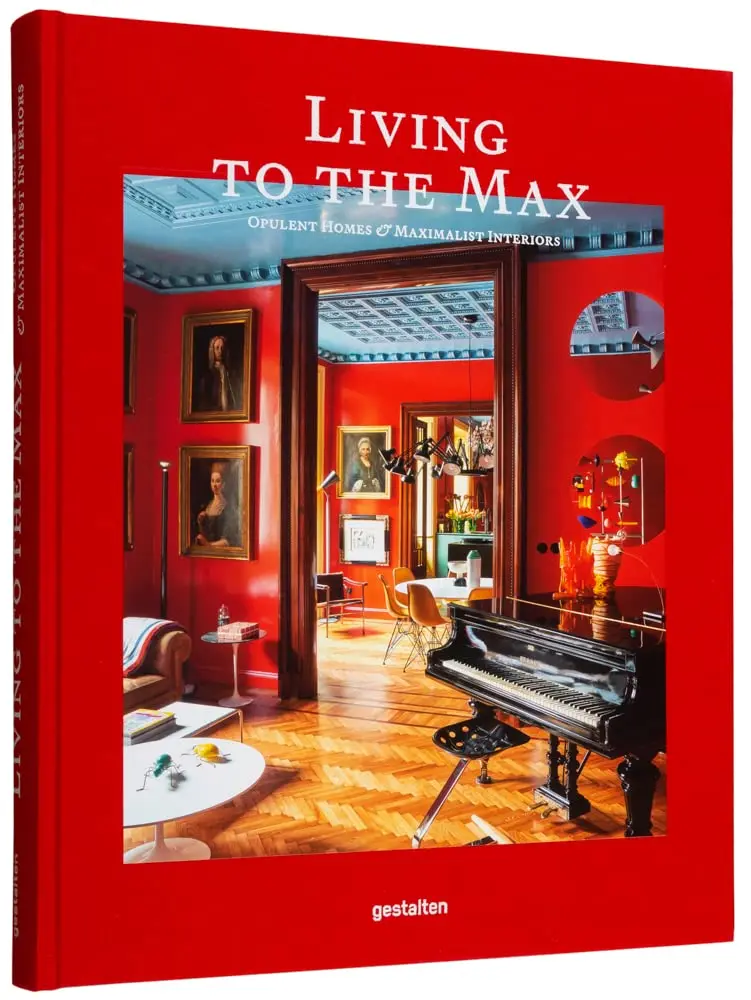 A red cover of a coffee table book titled Living To The Max, with a photo of an antique maximalist interior.