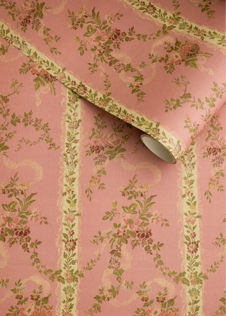 A closeup view of a Bridgerton-style wallpaper with floral designs on a pink background.