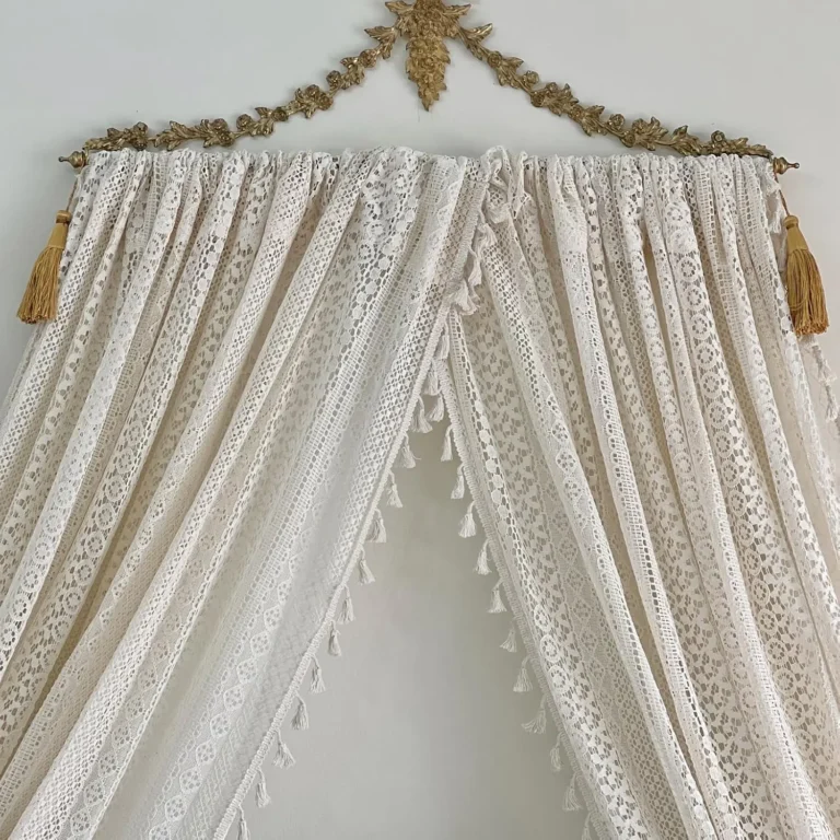 A cream lace canopy with tassels and a gold bed crown.